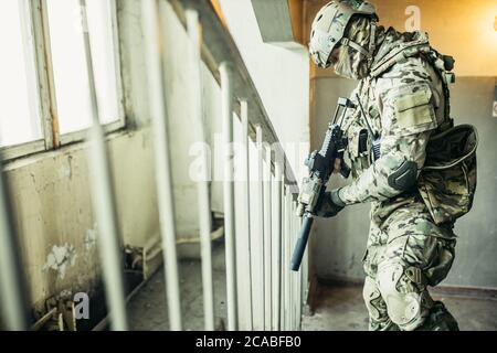 army concept. soldier with weapon in landing, climbing up the stairs, searching enemy to shoot, protect. Stock Photo