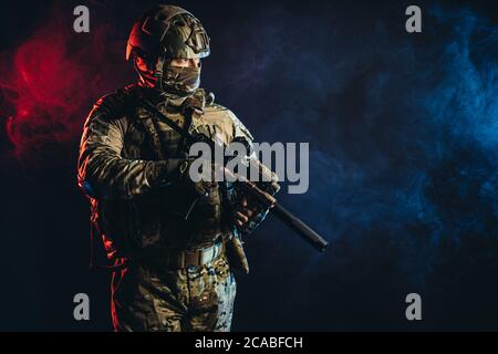 courageous soldier man in green military wear holding gun, rifle in hands, don't afraid of danger, looking for enemy Stock Photo