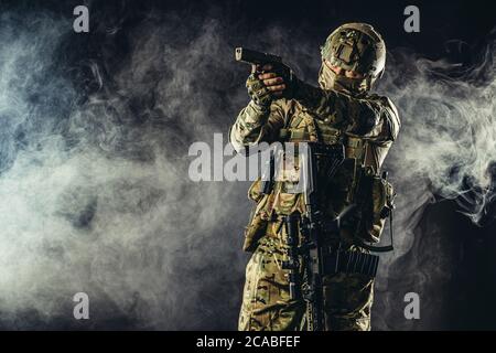 brave strong and confident man soldier wearing army clothes, green camouflage stand holding gun, ready to shoot Stock Photo