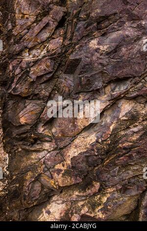 Closeup of dark dged shabby cliff cracks. Gray stone rock texture of mountains. Concept of geology and mountaineering Stock Photo