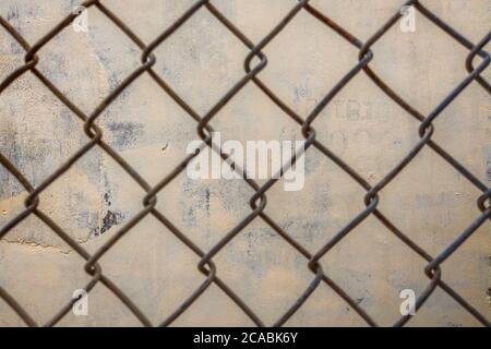 Close-up old iron wire fence vintage net on the background of concrete beige painted wall Stock Photo