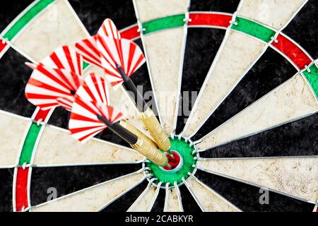 Success hitting target aim goal achievement concept background - three darts in bull's eye close up. red three darts arrows in the target center busin Stock Photo