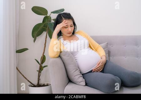 Pregnant woman getting a contraction in the living room at house Stock Photo