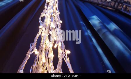Close up lights of garland on the wall. Glowing electric garland on a black background. Stock Photo