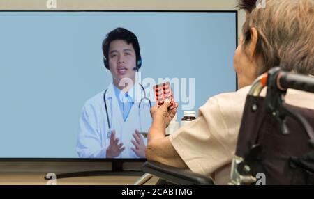 Elderly woman sit at home having online consultation with doctor on tablet computer. Stock Photo