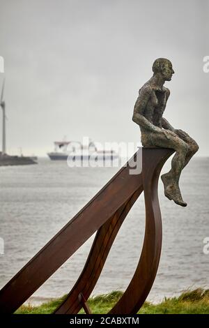 Heysham sculpture of SHIP and two figures at Half Moon Bay by artist Anna Gillespie near the port as the  ISLE OF MAN STEAM PACKET COMPANY ferry arriv Stock Photo