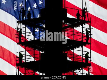 Construction workers on scaffolding with Stars and Stripes flag as backdrop. Concept image: USA, American economy, blue collar worker... Stock Photo