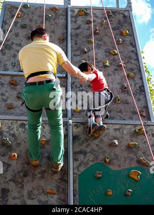 Father holding small child on climbing wall Stock Photo