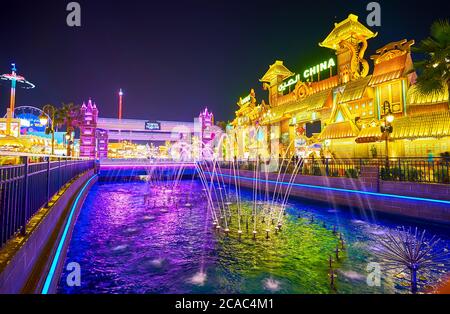 DUBAI, UAE - MARCH 5, 2020: The evening in Global Village with a view on scenic dancing fountains in canal and illuminated pavilions on its banks, on Stock Photo