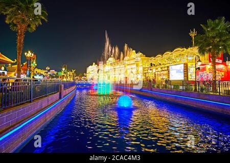 DUBAI, UAE - MARCH 5, 2020:  The colorful lighting fountains in narrow canal amid the trade pavilions of  Global Village Dubai, on March 5 in Dubai Stock Photo