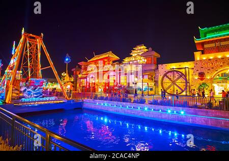 DUBAI, UAE - MARCH 5, 2020: The brightly lighted canal of Global Village Dubai with scenic trade and exhibition pavilions of Japan and South Korea on Stock Photo