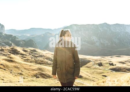 Young beautiful girl tourist or traveler walking alone on the background of a mountain landscape in autumn.