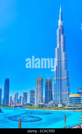 DUBAI, UAE - MARCH 3, 2020: The scenic view on magnificent Burj Khalifa building with surrounding skyscrapers and manmade Burj Lake on foreground, on Stock Photo