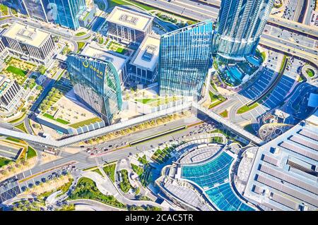 DUBAI, UAE - MARCH 3, 2020: The view from the top of Burj Khalifa on the roof of Dubai Mall and its footwalk bridges stretching along car roads, on Ma Stock Photo