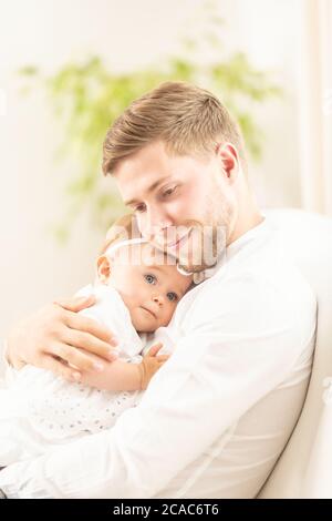 Father cuddles his daughter in his arms, both smiling and happy. Stock Photo