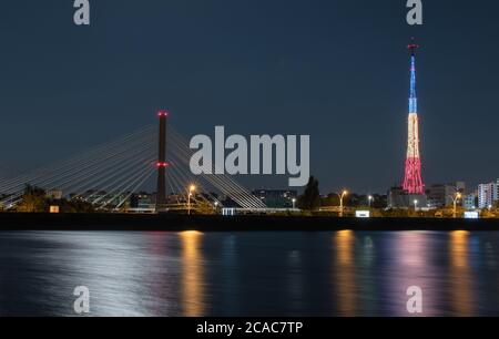 Light reflections in the water of the Mill Lake, coming from the tricolor illuminated tower, the street lighting and the road bridge Stock Photo