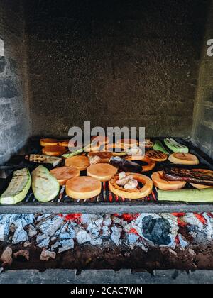 Grilled vegetables. Courgette, mushrooms and pumpkin on a metal grill over red coals. Stock Photo