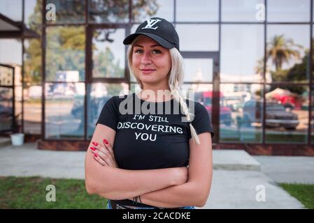 Sukhumi / Abkhazia - August 2, 2019: portrait of young blonde woman of russian ethnicity with black cap and t-shirt in city Stock Photo