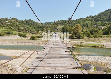 Sukhumi / Abkhazia - August 2, 2019: old soviet lada crossing narrow wooden suspension bridge Stock Photo