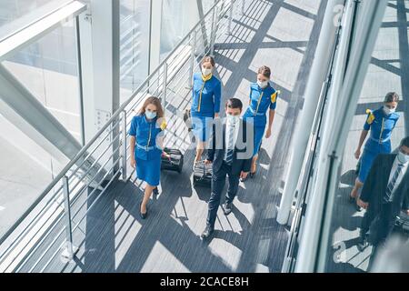 Pensive airline employees in face masks walking ahead Stock Photo