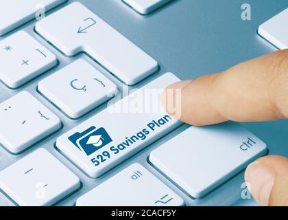 529 Savings Plan Written on Blue Key of Metallic Keyboard. Finger pressing key. Stock Photo