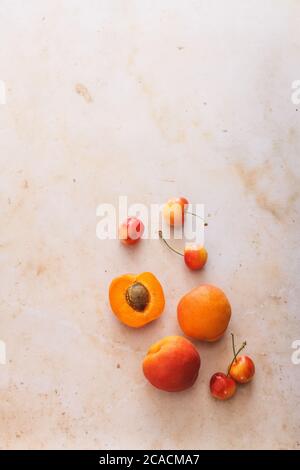 Healthy summer fruit: isolated apricots and cherries on a pink marble backdrop Stock Photo