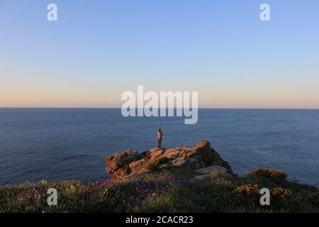 Figure standing on coastal rocks Stock Photo