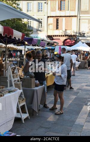Limoux Aude France Couple at French market. Man using mobile phone. Woman wearing face mask standing by unmasked partner. Stock Photo