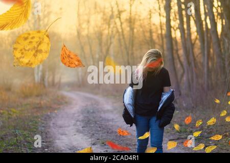 Sad woman walking away alone.  Beautiful sad lonely girl  walking away in autumn forest. Stock Photo