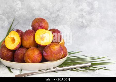 Fresh plums are yellow-red. Juicy and large. Purchase of goods for future use. Vitamins for immunity. On a light background. Copy space Stock Photo