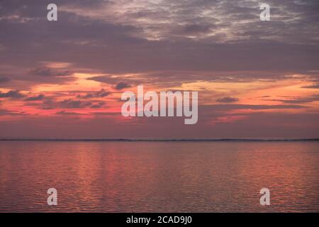 red sunrise cloudy sky in maldives. Peaceful sea waves on horizon Stock Photo