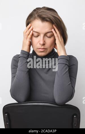 The woman is holding her head. Headache. Fatigue. Stock Photo