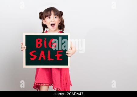 big sale discount for item in shopping mall promotion on end of year concept : adorable girl act surprise face holding chalk sign board , big sale Stock Photo