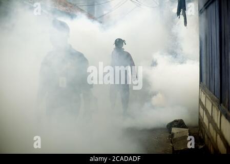 Officers from local health office conducting insecticide fogging session, a dengue fever outbreak prevention in a dense populated area of Jakarta. Stock Photo