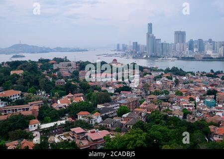 aerial view of Gulangyu(Kulangsu) Island in Xiamen,Fujian,China. Houses and trees. Modern skyscrapers on the other side of the river. Stock Photo