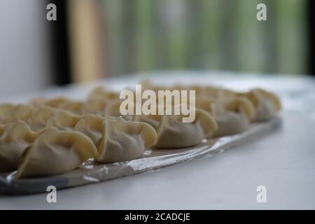Close up many raw dumplings placed in good order on white table. Blur background. Traditional Chinese food. Stock Photo