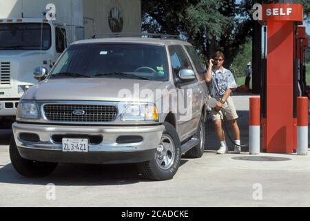 Austin Texas USA: Anglo male talking on cell phone while filling-up a gas-guzzling sport utility vehicle at gas station. ©Bob Daemmrich Stock Photo