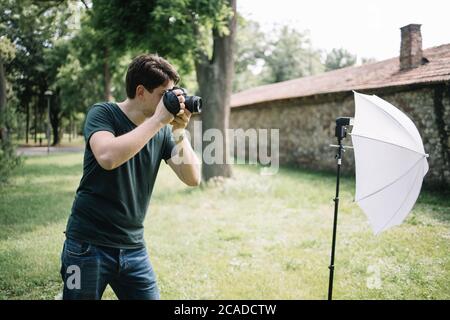 Side view of man holding professional camera and taking photos Stock Photo
