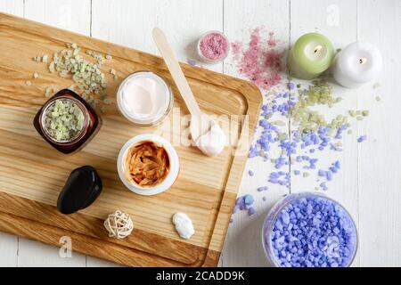Top view. Beautiful spa composition on massage table in wellness center, copyspace. Accessories for relaxing treatments and personal care. Towels, oils, serum, sea salts and scrubs. Decorative candles. Stock Photo