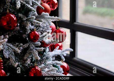 close up red balls on christmas tree. blur window as background Stock Photo