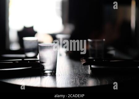 close up empty drinking glass on wooden dining table. Blur tableware and dark background Stock Photo