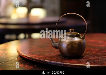 close up one old copper teapot on wooden table. Traditional Chinese tea kettle. Bokeh background Stock Photo