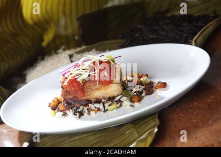 Roast pork tenderloin served on wild rice and fried plantain chips and dipped in gravy Stock Photo