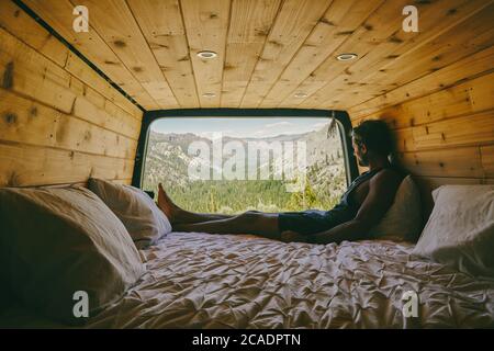 Young man sitting on bed of camper van observing the views of Yosemite Stock Photo