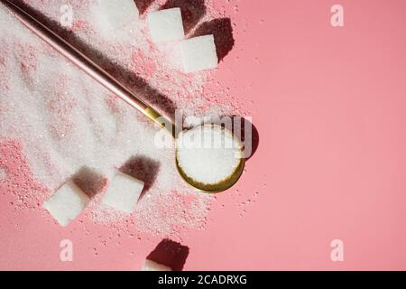 White sugar in the spoon and sugar cubes on pink Stock Photo