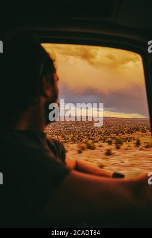 Young man gazing out to sunset while driving in desert of Moab, Utah. Stock Photo
