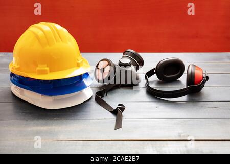 Work safety protection equipment. Industrial protective gear on wooden table, red color background. Construction site health and safety concept Stock Photo