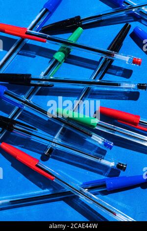 Pens: pattern of green, black blue and red colored pens from above on blue background. Office and school concept Stock Photo