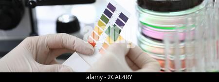 Gloved hands holding paper to test soil acidity Stock Photo