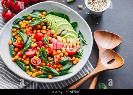 Fresh healthy salad with chickpea, avocado, cherry tomatoes and spinach. Stock Photo